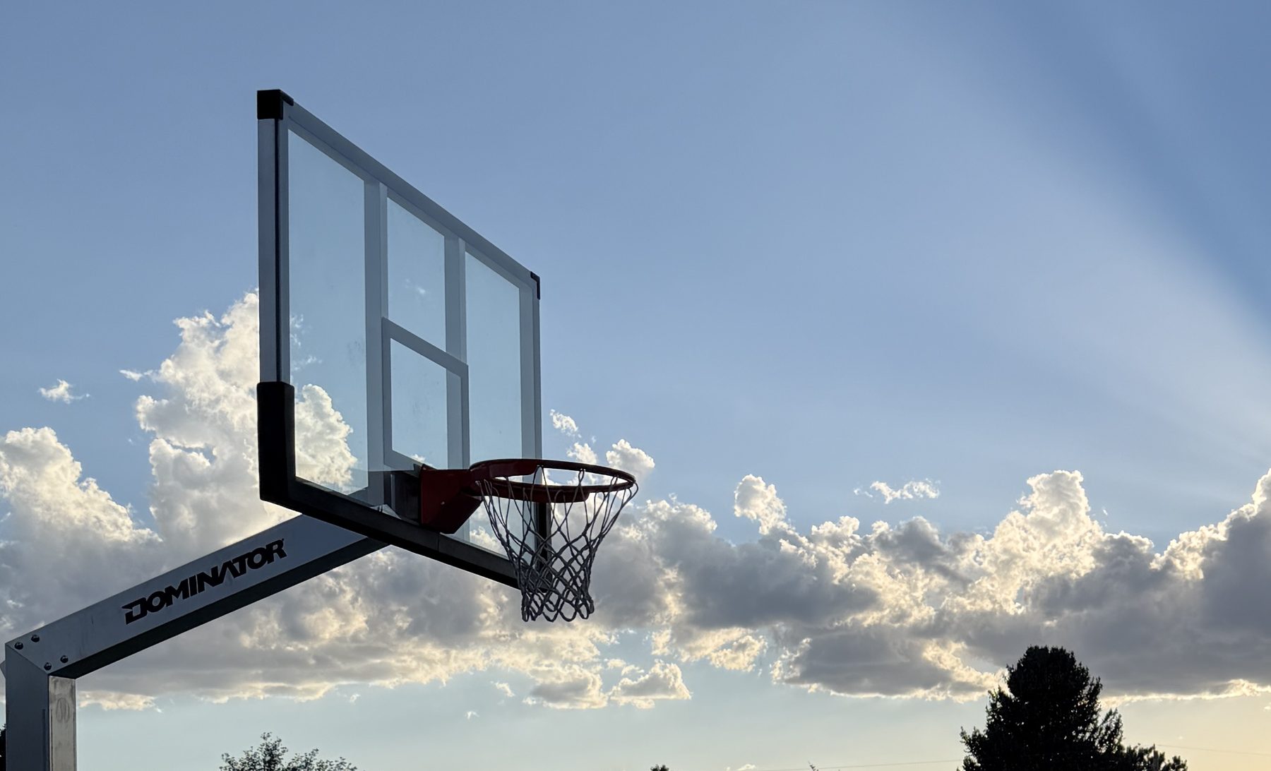 Glass backboard and hoop against evening clouds